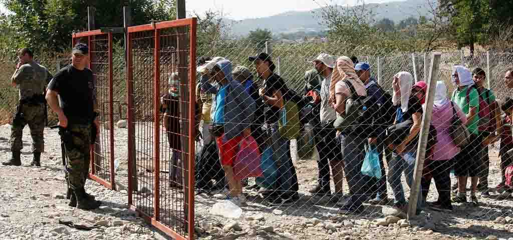 Un grup de persones refugiades davant un pas fronterer